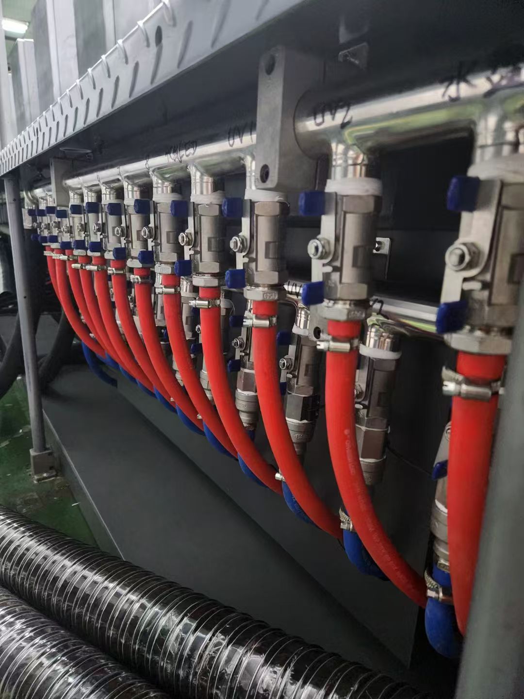 Close-up of a water-cooled UV LED curing manifold with red cooling lines installed on industrial printing equipment.