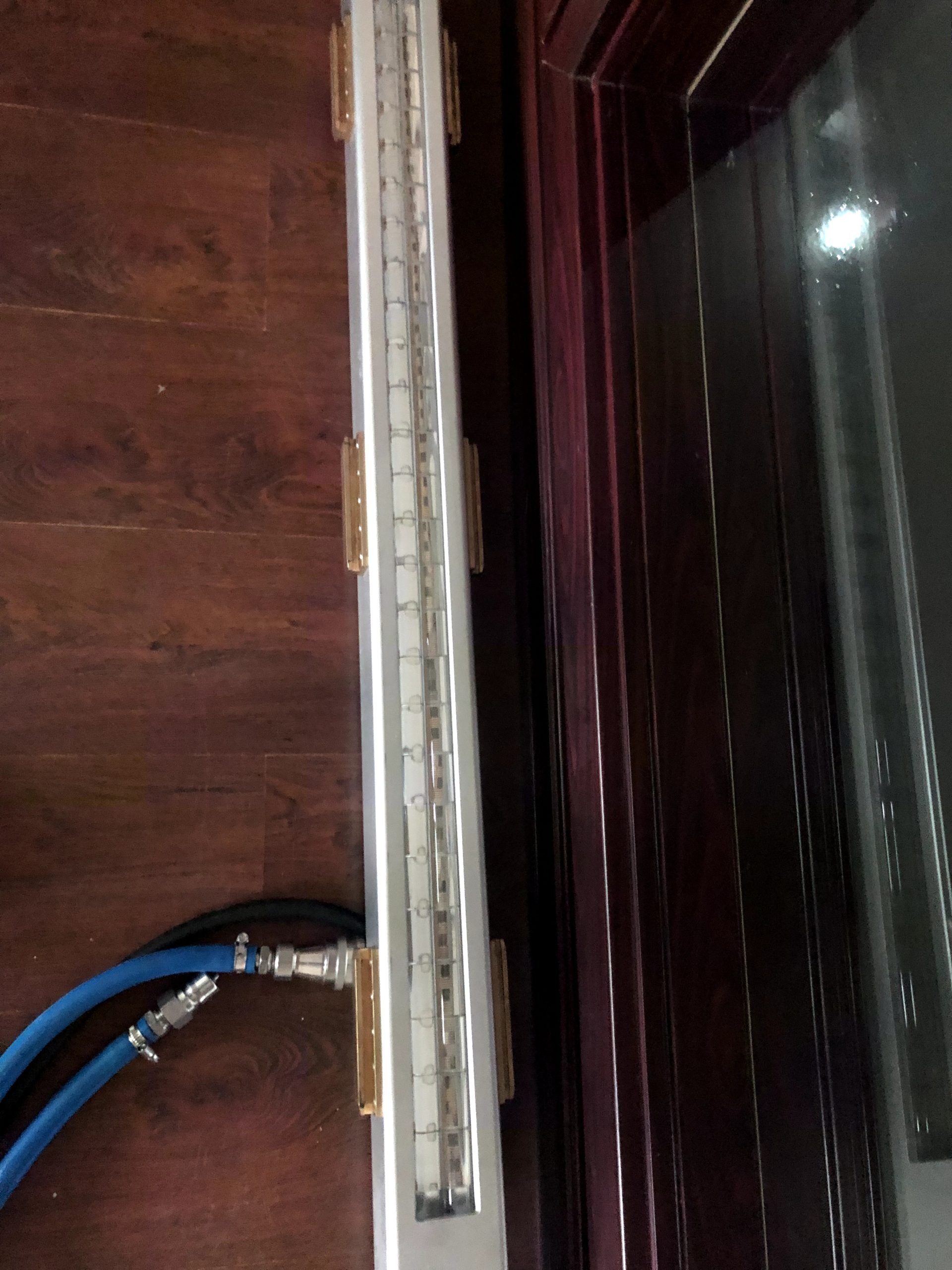 Linear UV LED curing lamp head positioned next to a wood surface for coating and finishing applications.
